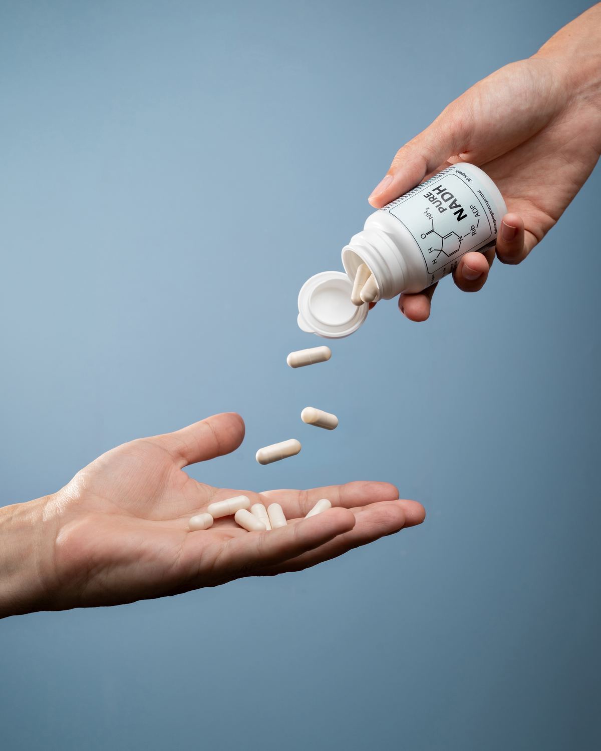Capsules being poured from a PureNADH bottle into an open hand